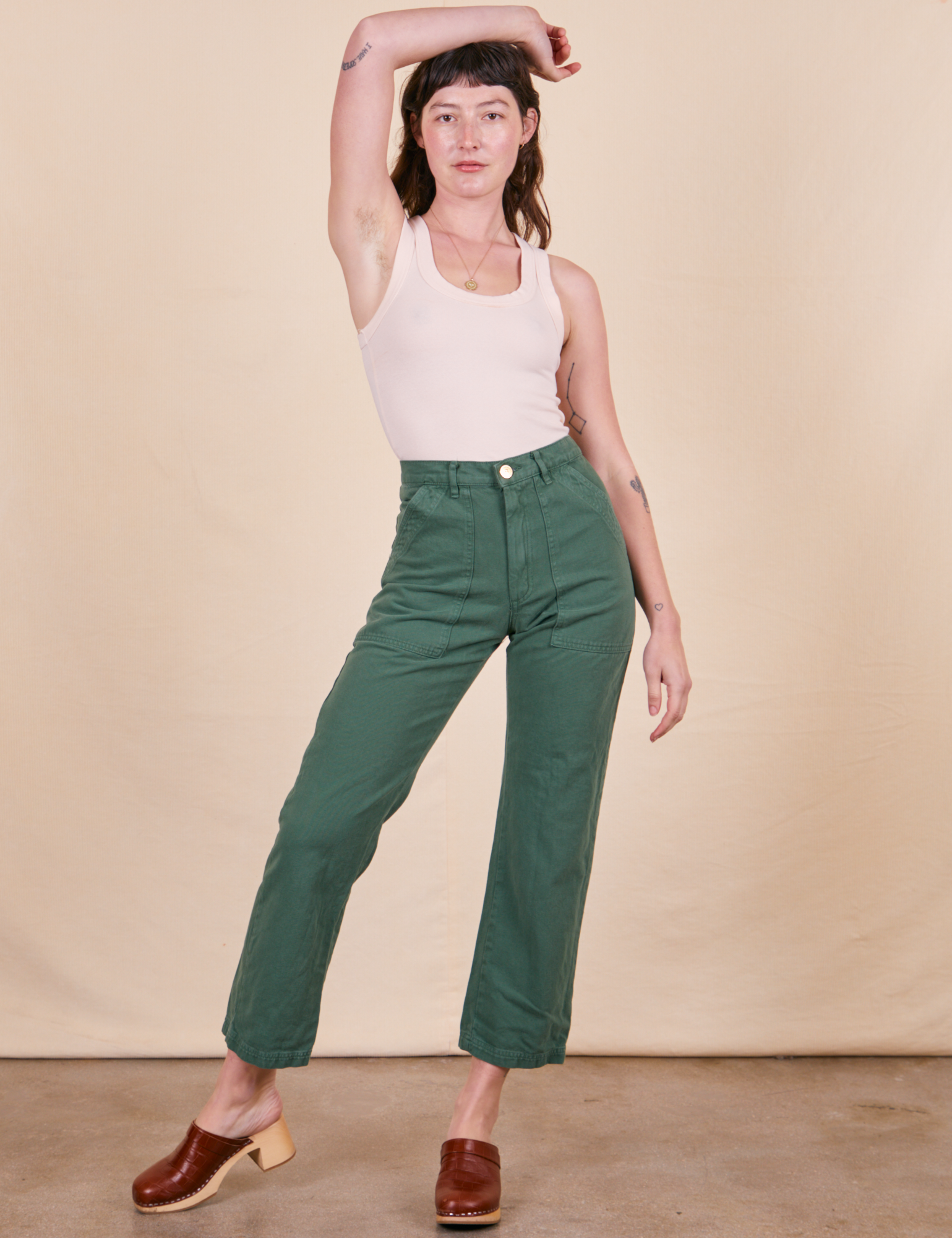 Alex is 5&#39;8&quot; and wearing XS Work Pants in Dark Emerald Green paired with vintage off-white Tank Top