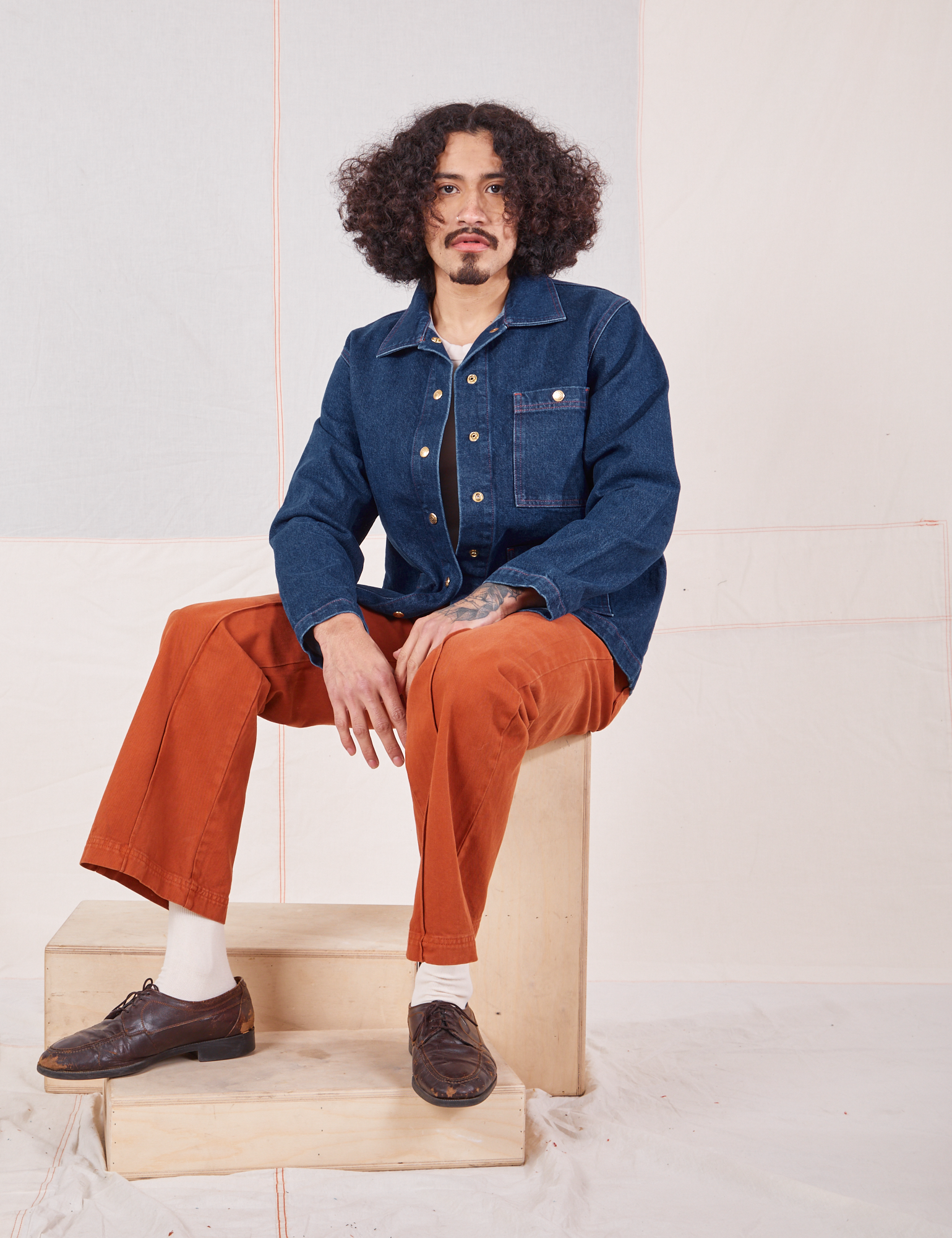 Jesse is wearing Indigo Denim Work Jacket in Dark Wash and burnt terracotta Western Pants