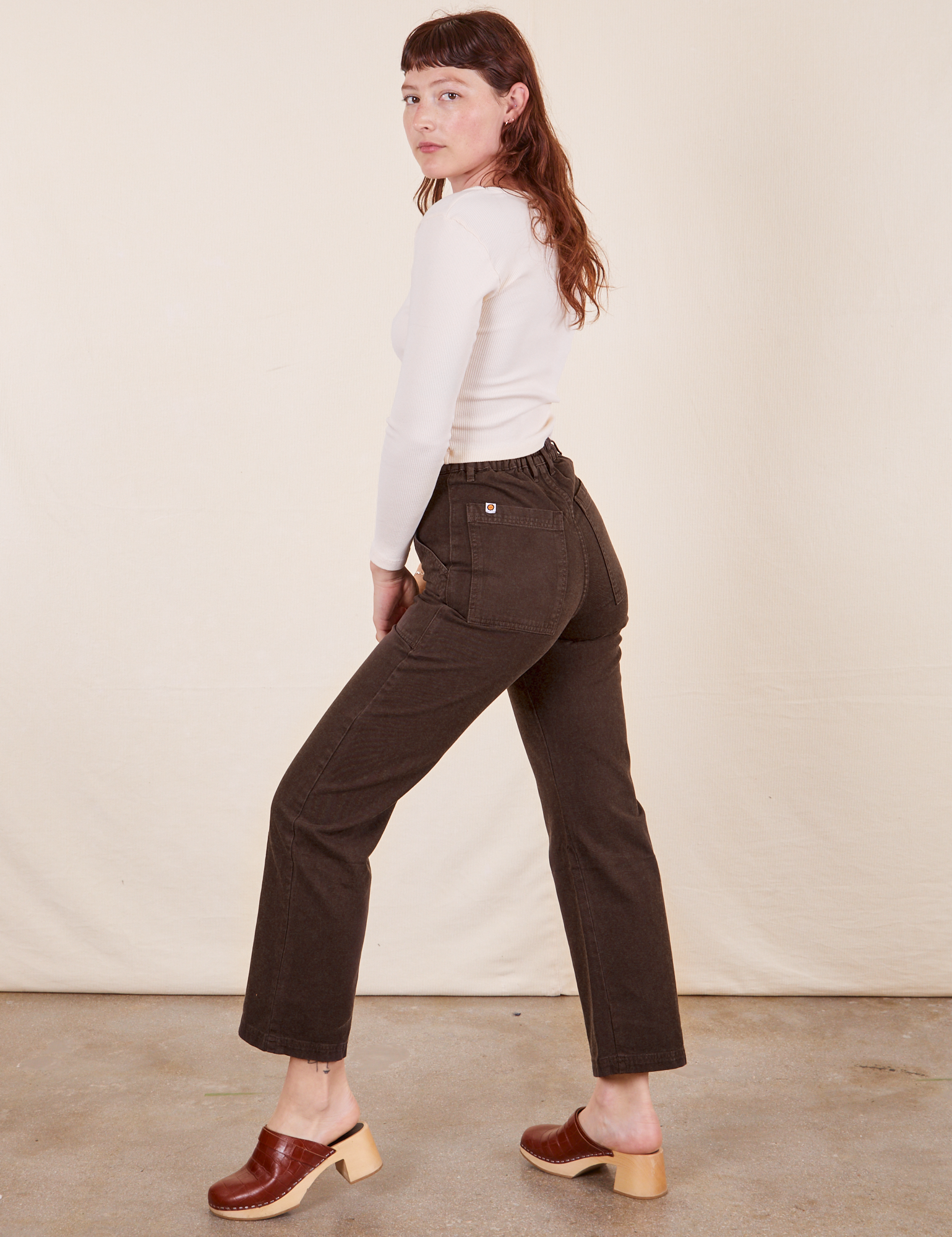 Side view of Work Pants in Espresso Brown and Long Sleeve V-Neck Tee in  vintage tee off-white on Alex