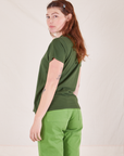 Angled back view of Organic Vintage Tee in Dark Emerald Green and gross green Western Pants worn by Alex