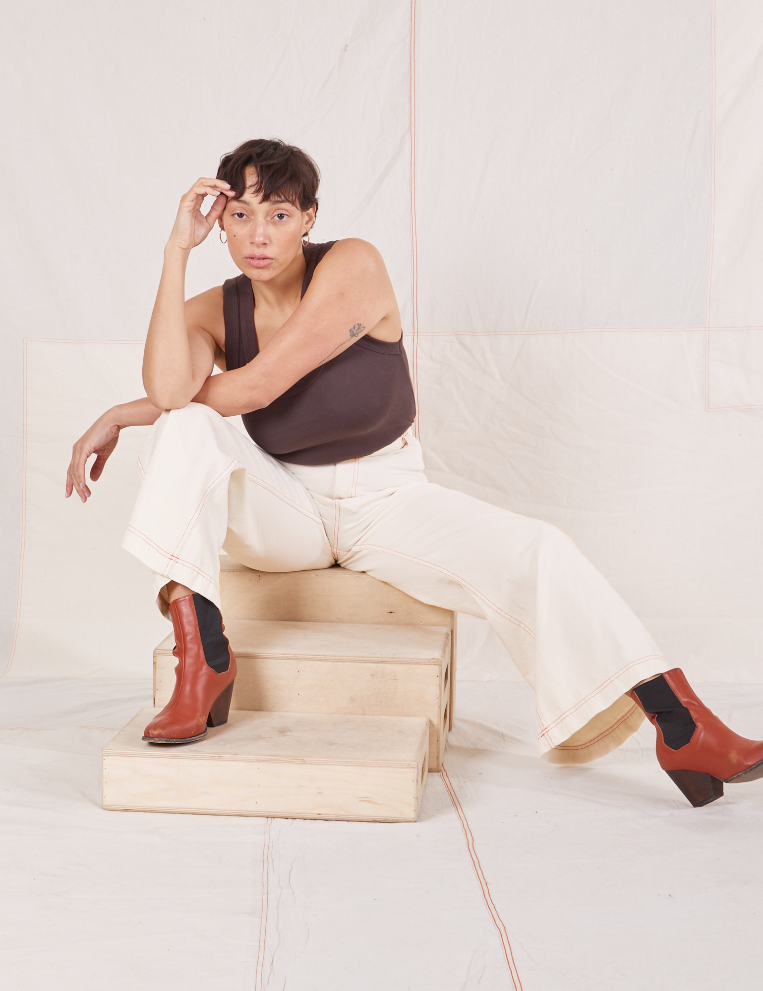 Tiara is sitting on a wooden crate. She is wearing Bell Bottoms in Vintage Tee Off-White and espresso brown Tank Top