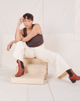Tiara is sitting on a wooden crate. She is wearing Bell Bottoms in Vintage Tee Off-White and espresso brown Tank Top