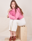 Essential Turtleneck in Bubblegum Pink on Allison wearing vintage off-white Western Pants sitting on wooden crates