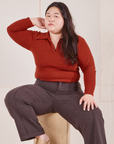 Ashley is sitting on a wooden crate wearing Long Sleeve Fisherman Polo in Paprika and espresso brown Western Pants