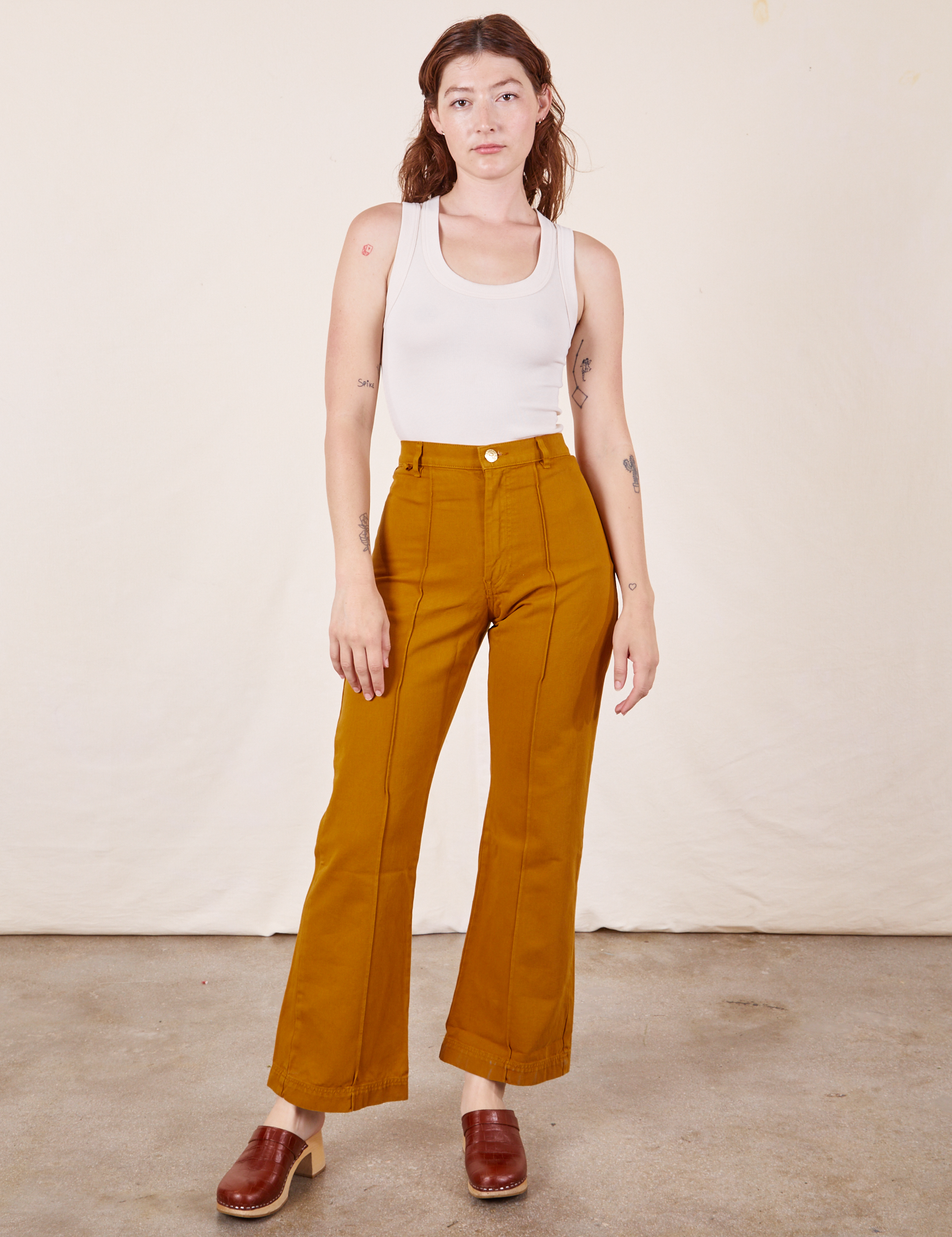 Alex is 5&#39;8&quot; and wearing XS Western Pants in Spicy Mustard paired with vintage off-white Tank Top
