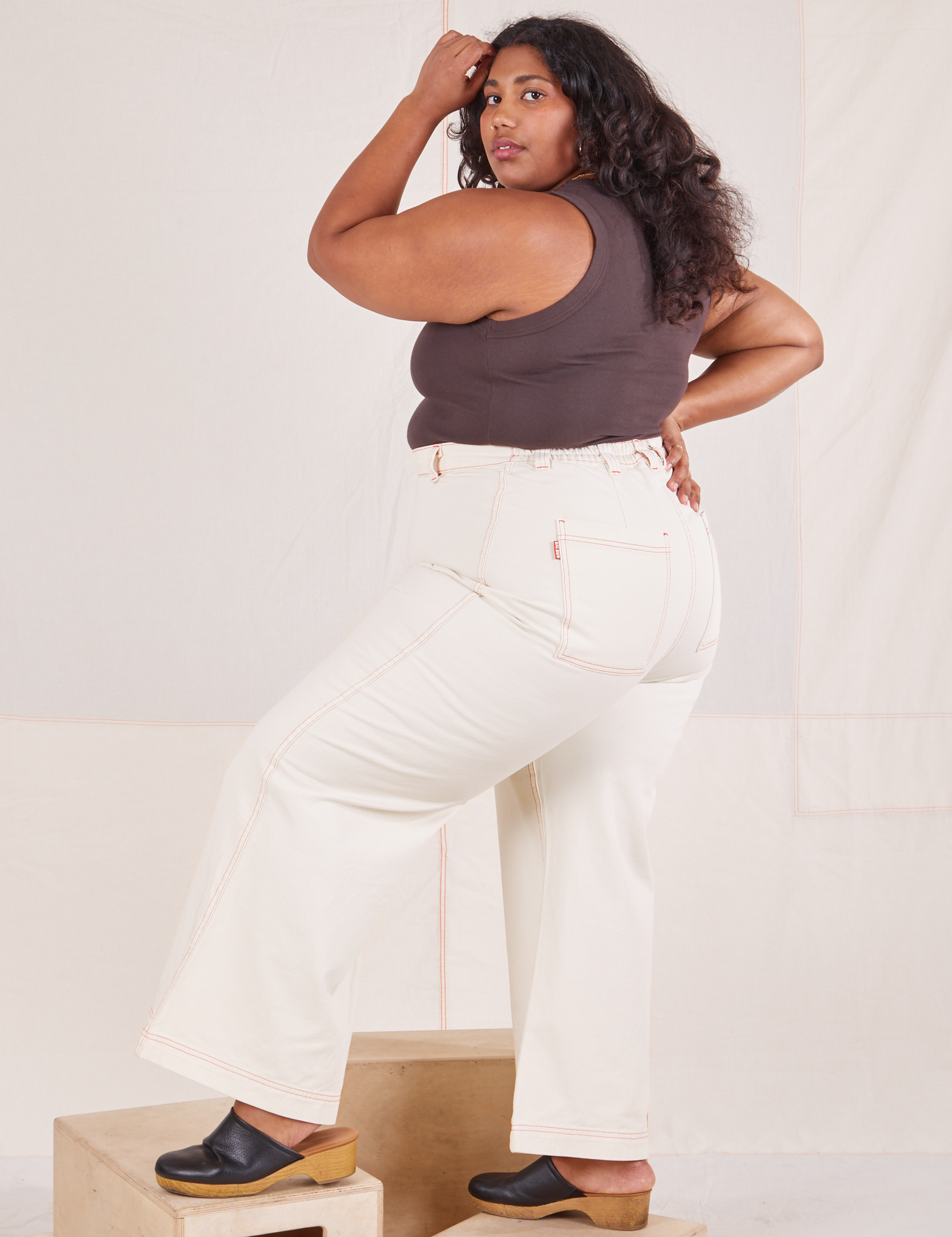 Angled back view of Bell Bottoms in Vintage Tee Off-White and espresso brown Tank Top worn by Morgan
