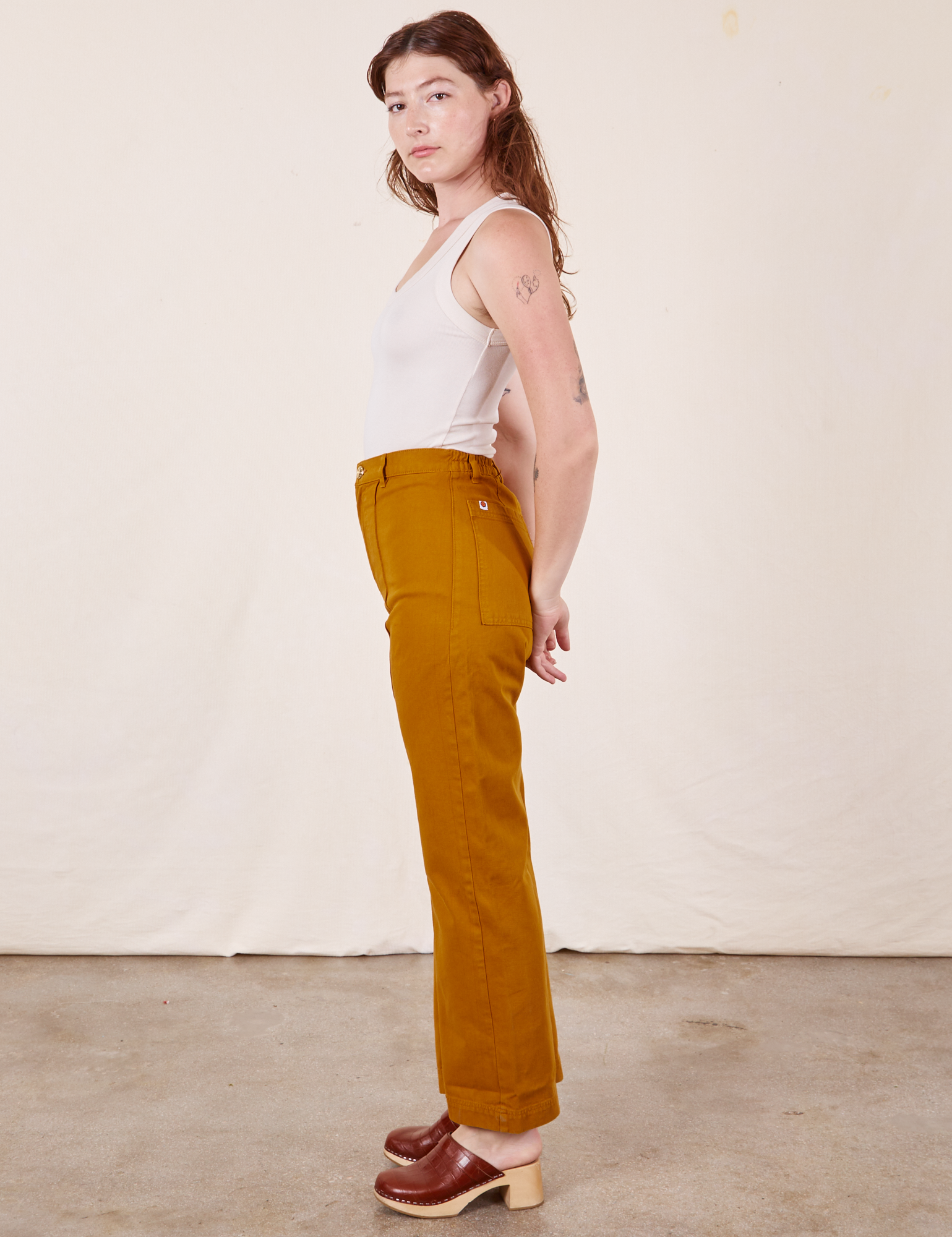Side view of Western Pants in Spicy Mustard and vintage off-white Tank Top worn by Alex