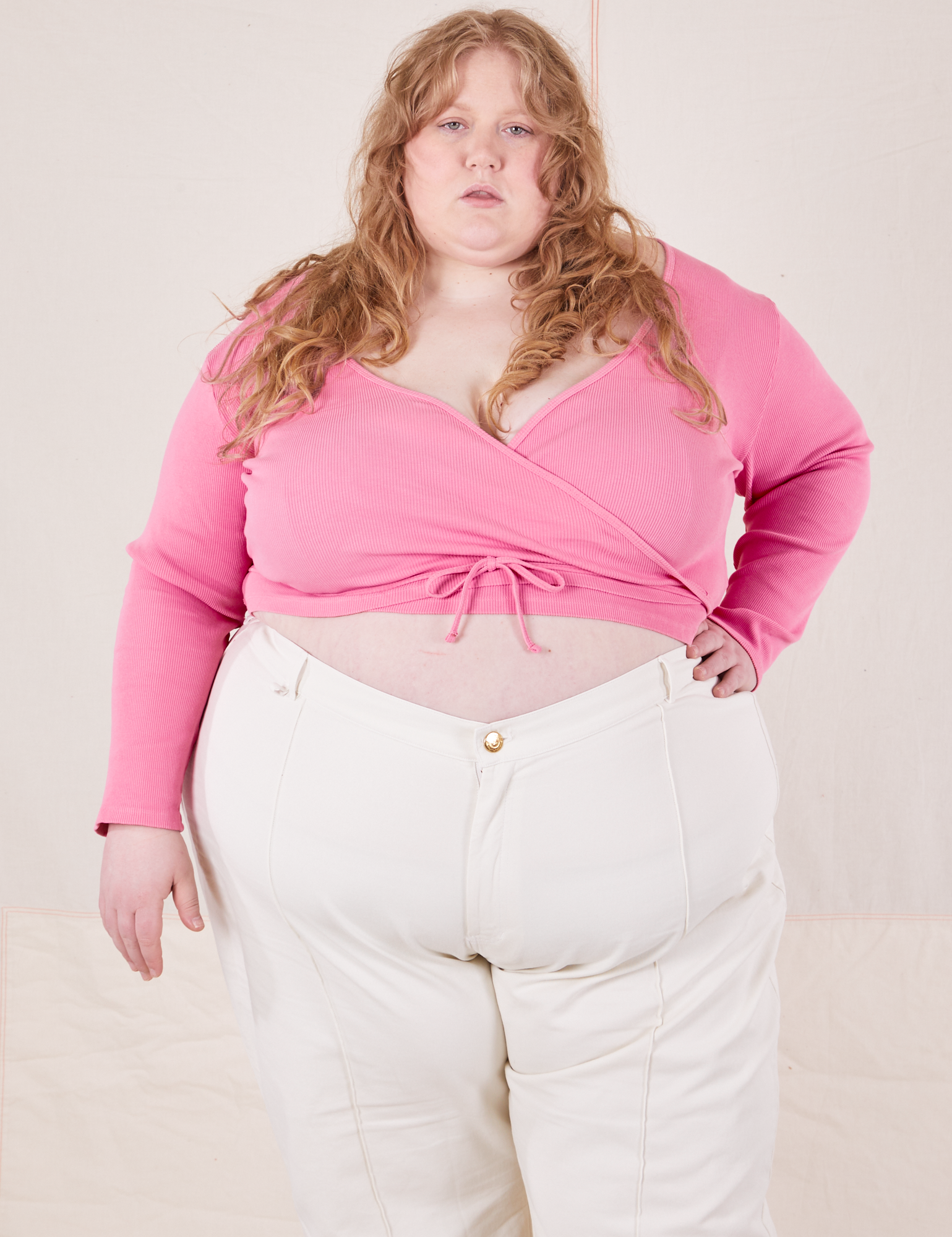 Catie is wearing size 6 Wrap Top in Bubblegum Pink paired with vintage tee off-white Western Pants