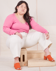 Ashley is sitting on a wooden crate wearing Long Sleeve V-Neck Tee in Bubblegum Pink and vintage tee off-white Western Pants