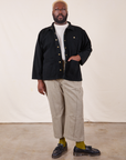 Elijah is 6'4" and wearing 3XL Denim Work Jacket in Basic Black paired with khaki gray Western Pants. He has his right hand in the jacket pocket.