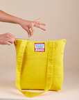 Over-Shoulder Zip Mini Tote in golden yellow being unzipped by model