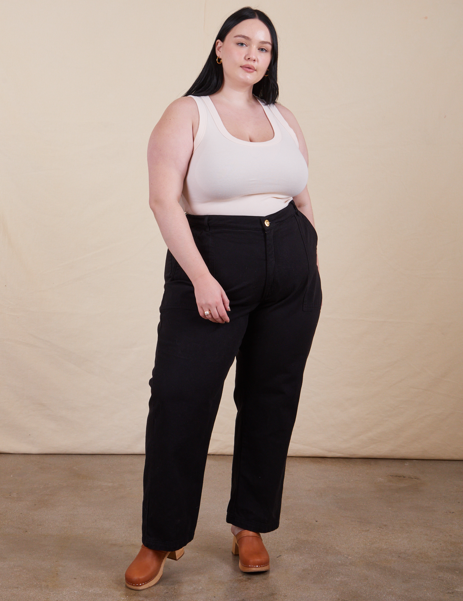 Kenna is 5&#39;8&quot; and wearing 1XL  Work Pants in Basic Black paired with a vintage off-white Tank Top