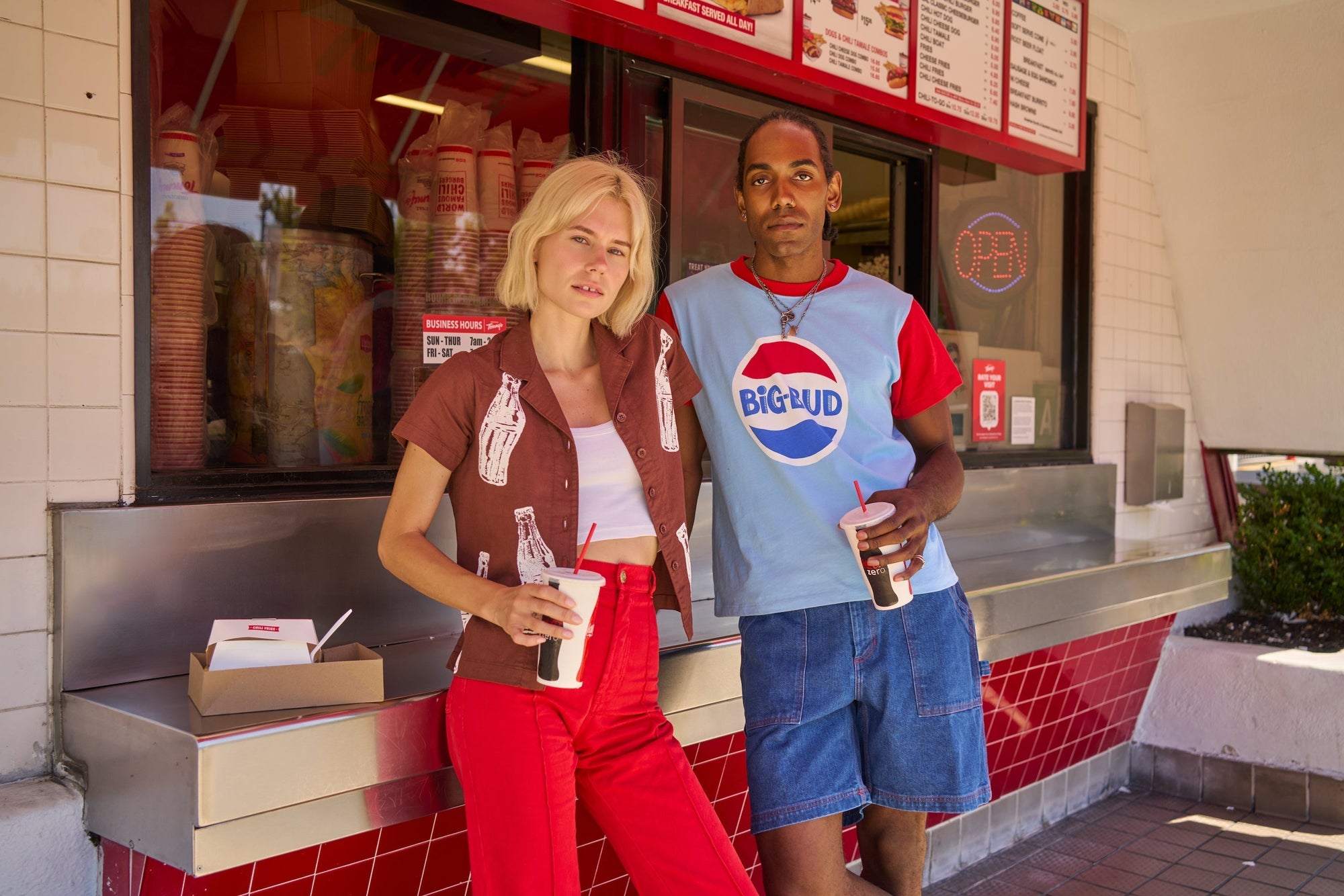 Madeline is wearing and Soda Bottle Pantry Button-Up in Fudgesicle Brown and Western Pants in Mustang Red. Jerrod is wearing Vintage Tee in Cola and Carpenter Shorts in Dark Wash.