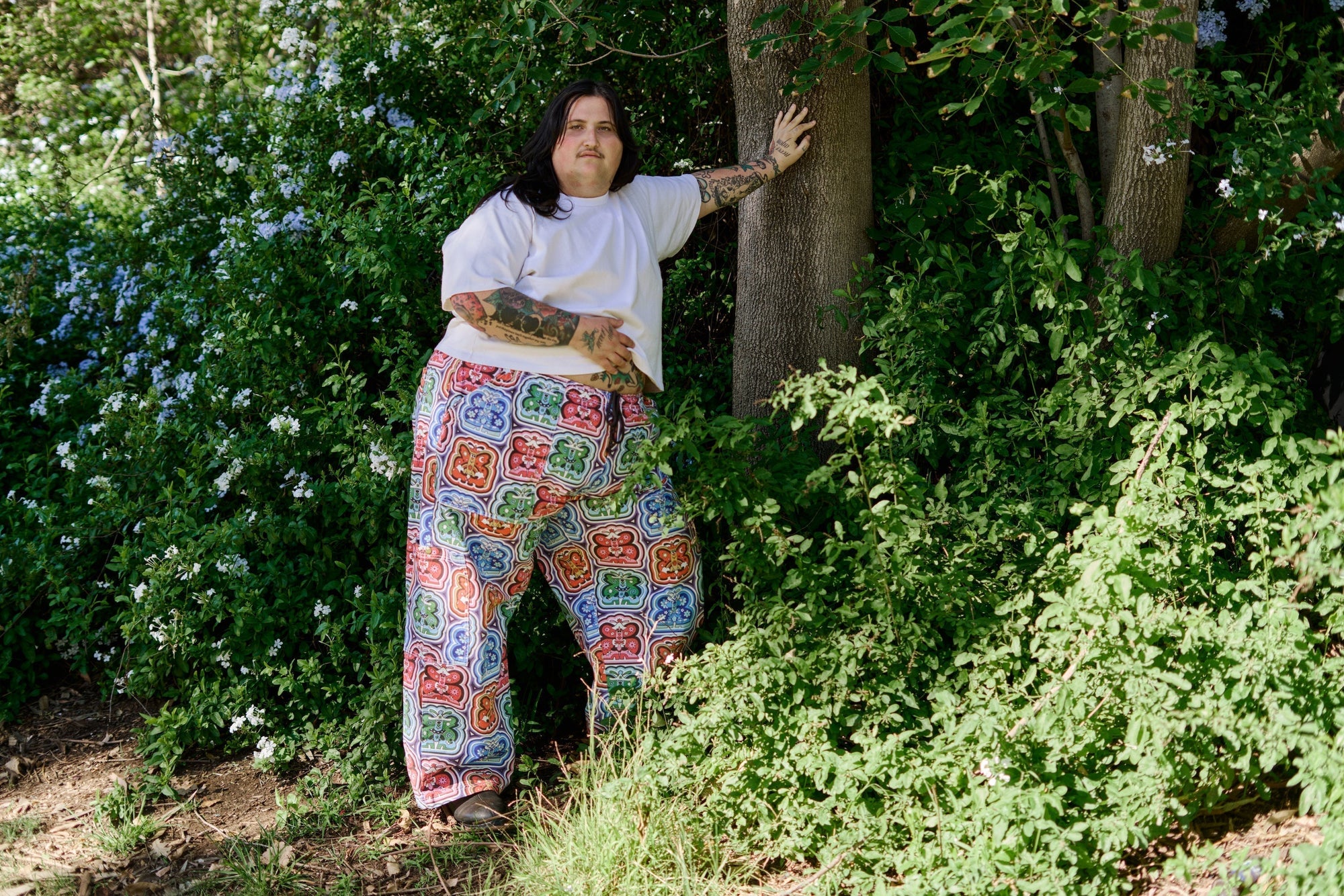 Sam is wearing Butterfly Kaleidoscope Drop Pocket Cargo Pants paired with Burly Tee in Vintage Tee White