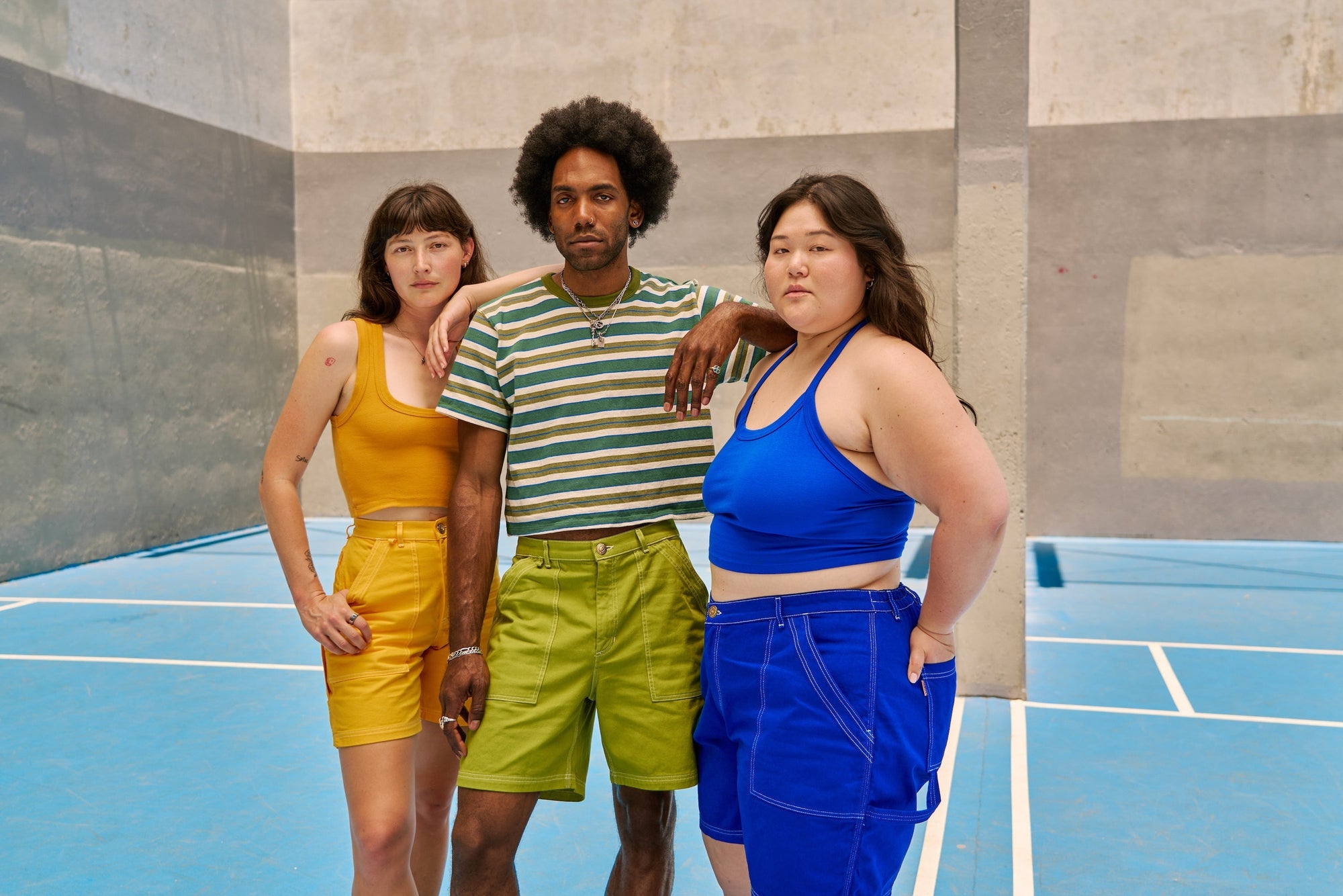 Ashley is wearing 10oz Carpenter Shorts in Royal Blue and matching Halter Top. Alex is wearing 10oz Carpenter Shorts in Sunshine Yellow. Jerrod is wearing 10oz Carpenter Shorts in Gross Green with a Blue & Green Burly Tee