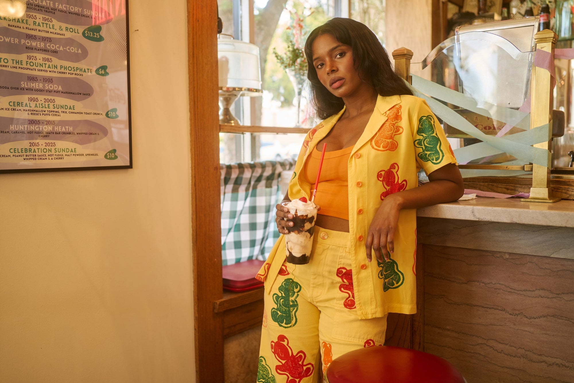 Kandia is wearing Gummy Bear Pantry Button-Up, matching Work Pants and Cropped Tank in Creamisicle