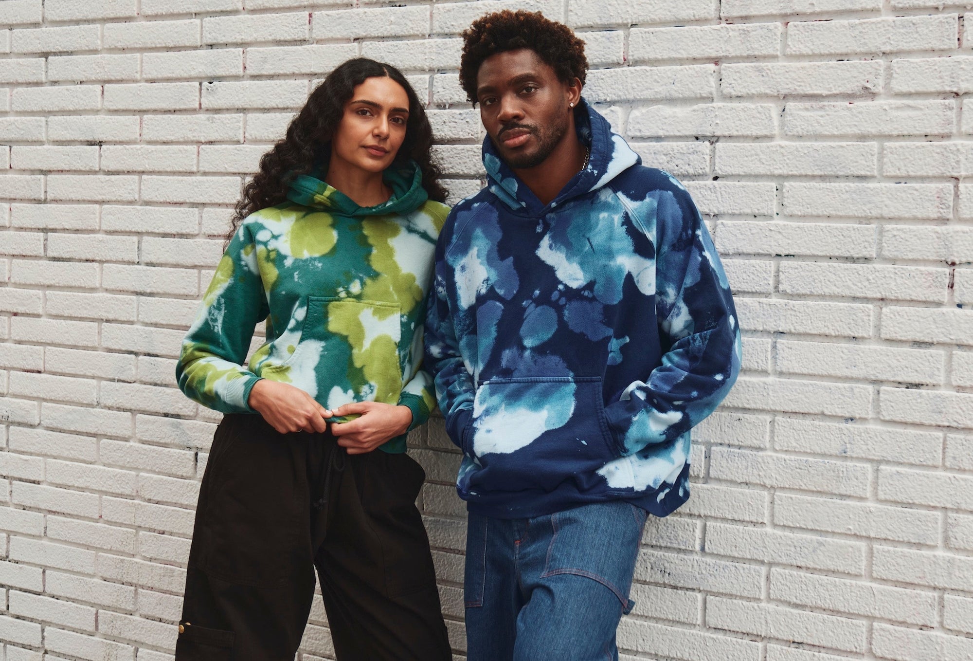 Isaac is wearing Heavyweight Oversized Hoodie in Blue Magic Waters and Carpenter Jeans in Dark Wash. Shahana is wearing Heavyweight Oversized Hoodie in Green Magic Waters and Drop Pocket Cargo Pants in Basic Black.