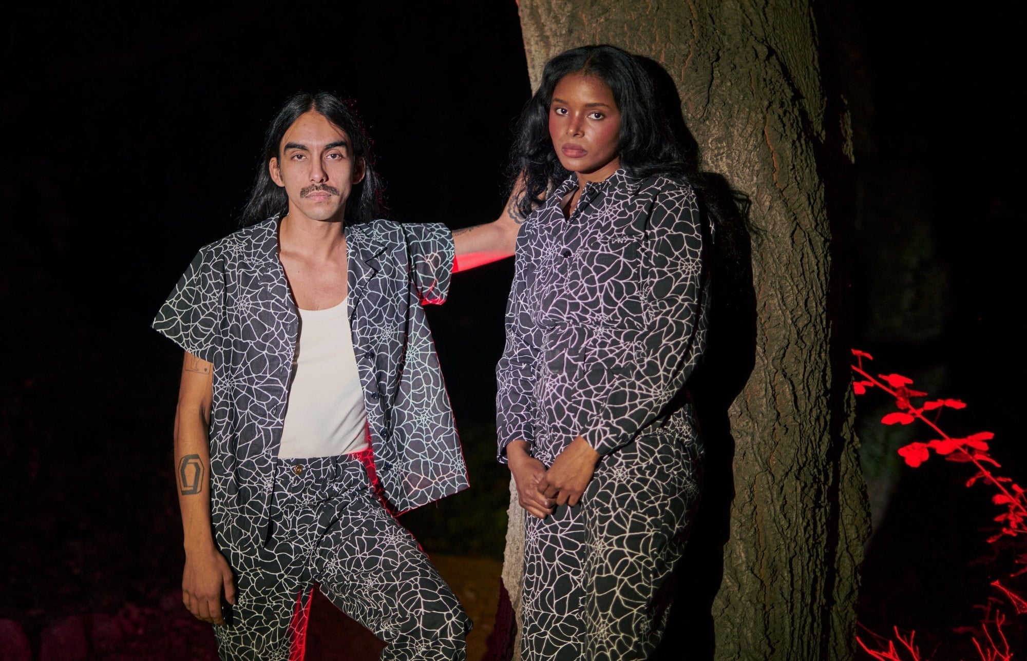 Anthony is wearing Pantry Button-Up and Work Pants in Spider Webs. Kandia Nzinga is wearing Long Sleeve Jumpsuit in Spider Webs.