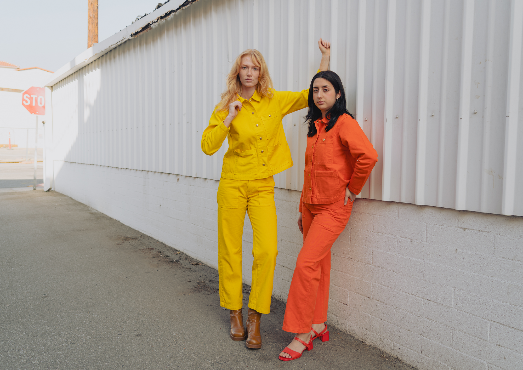 Margaret is wearing  Work Jackets in Golden Yellow with matching Work Pants.  Betty is wearing Work Jackets in Construction Orange with matching Work Pants. 