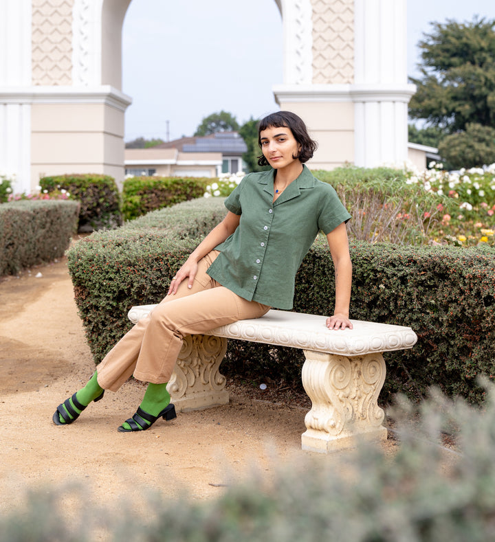 Soraya wearing Pantry Button-Up in Dark Emerald Green and Petite Work Pants in Tan