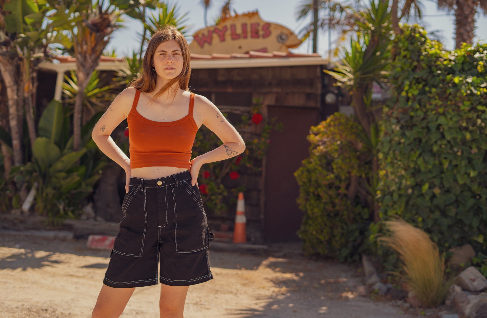 Scarlett is wearing Cropped Cami in Burnt Terracotta and Carpenter Shorts in Basic Black