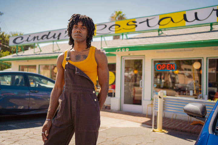 Jerrod is wearing Original Overalls in Mono Espresso and Tank Top in Mustard Yellow