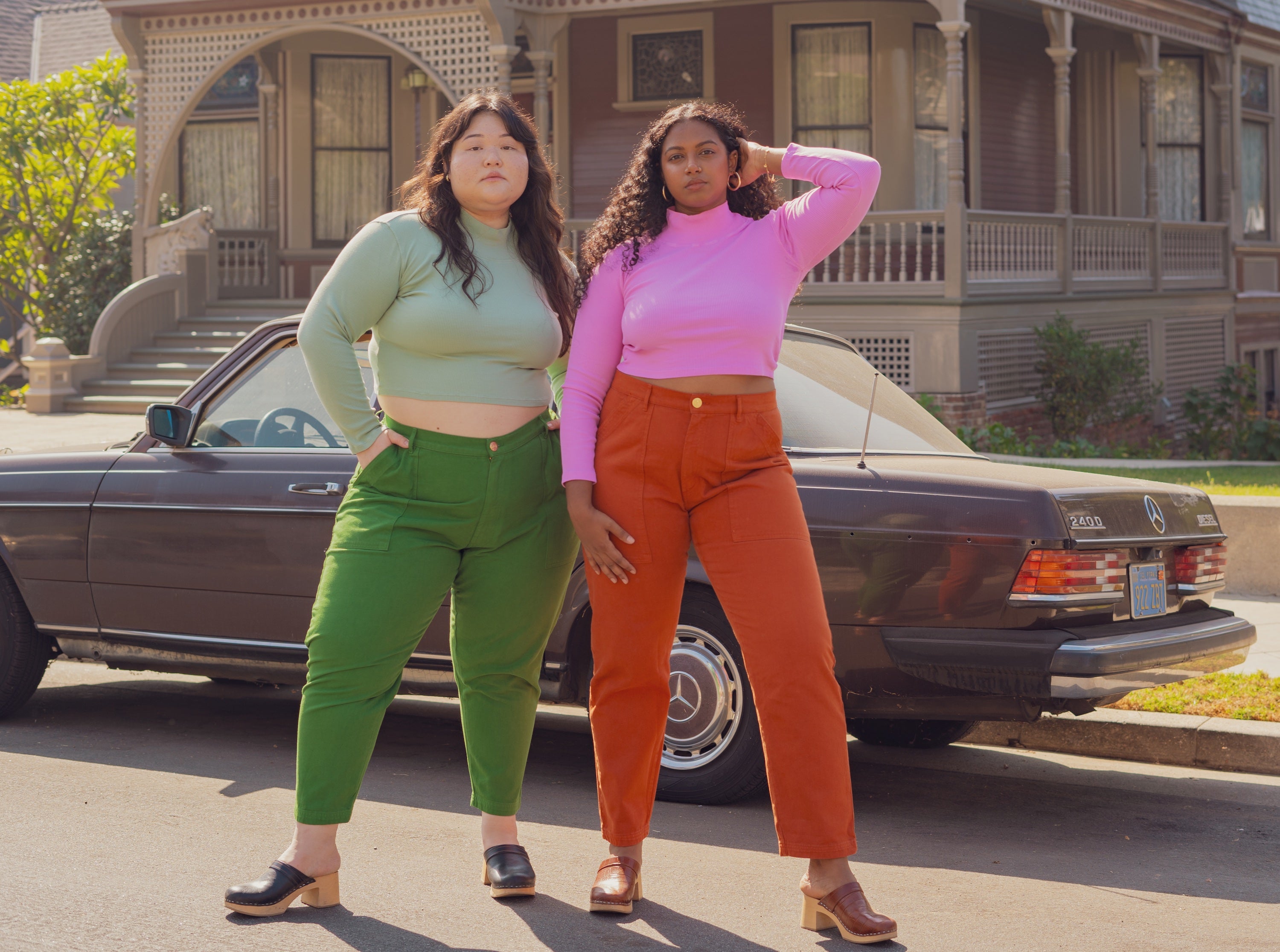 Ashley is wearing Essential Turtleneck in Sage and Petite Pencil Pants in Lawn Green. Meghna is wearing Essential Turtleneck in Bubblegum Pink and Pencil Pants in Burnt Terracotta