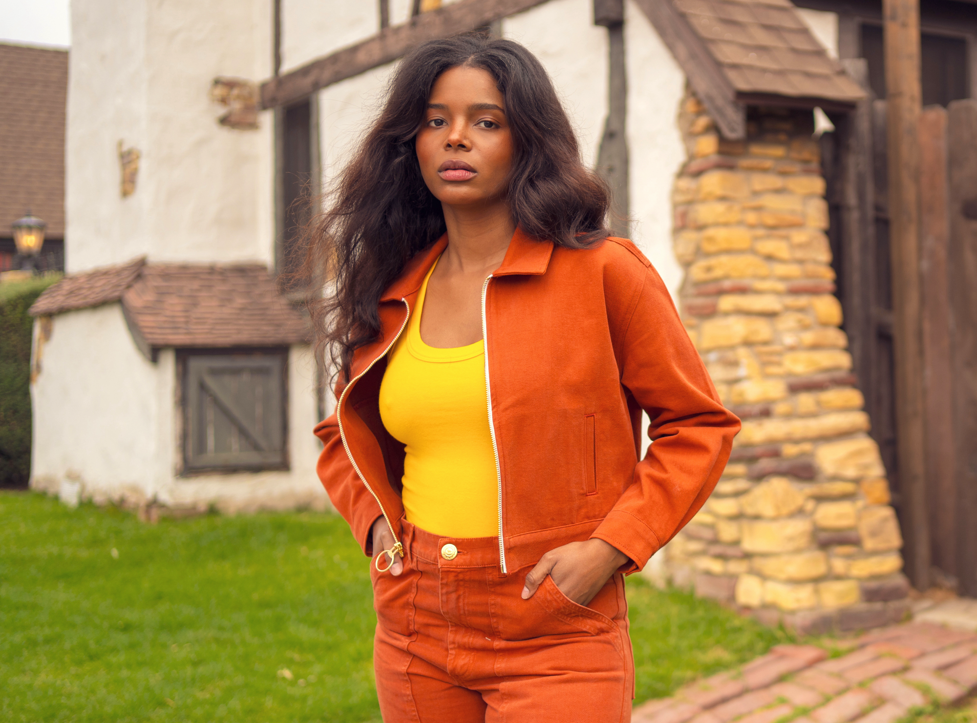 Kandia is wearing Ricky Jacket in Burnt Terracotta, Tank Top in Sunshine Yellow, and Work Pants in Burnt Terracotta