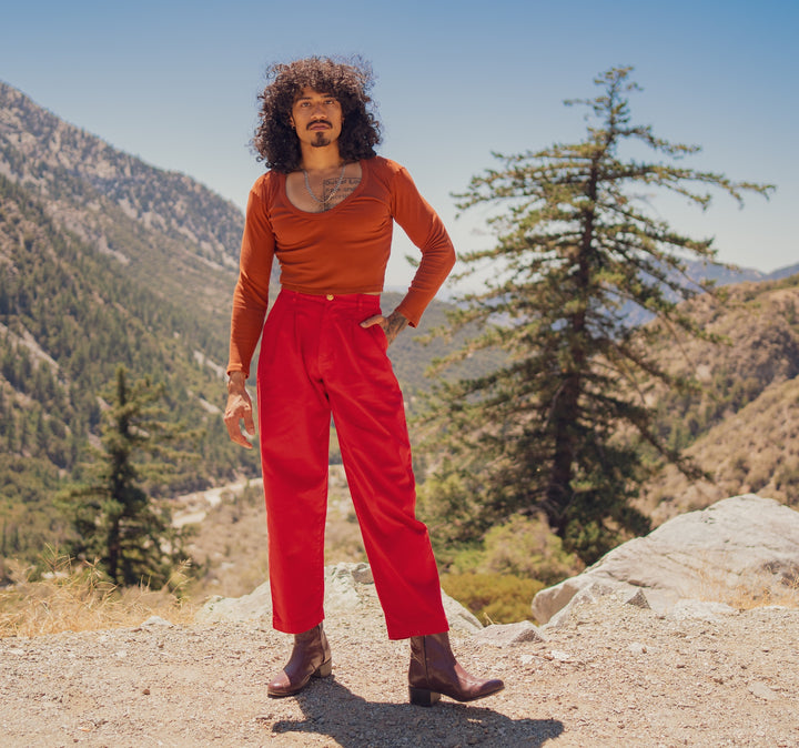 Jesse is wearing Heavyweight Trousers in Mustang Red and Long Sleeve V-Neck Tee in Burnt Terracotta