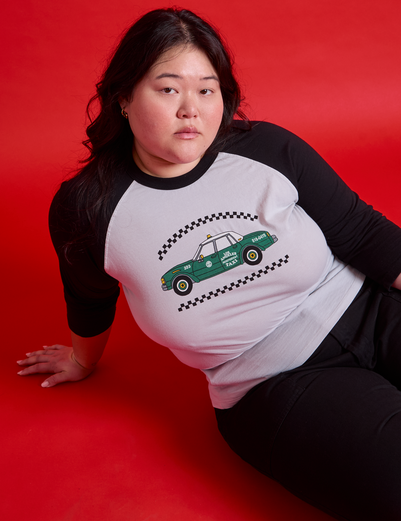 Ashley is wearing a Taxi Raglan Tee in Los Angeles. White body with black sleeves.