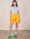 Alex is 5'8" and wearing XXS Sweat Shorts in Sunshine Yellow paired with a Jr. Varsity Tee in Stone White