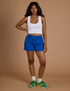 Kandia is 5’3” and wearing XXS Athletic Shorts in Royal Blue paired with vintage tee white Cropped Tank
