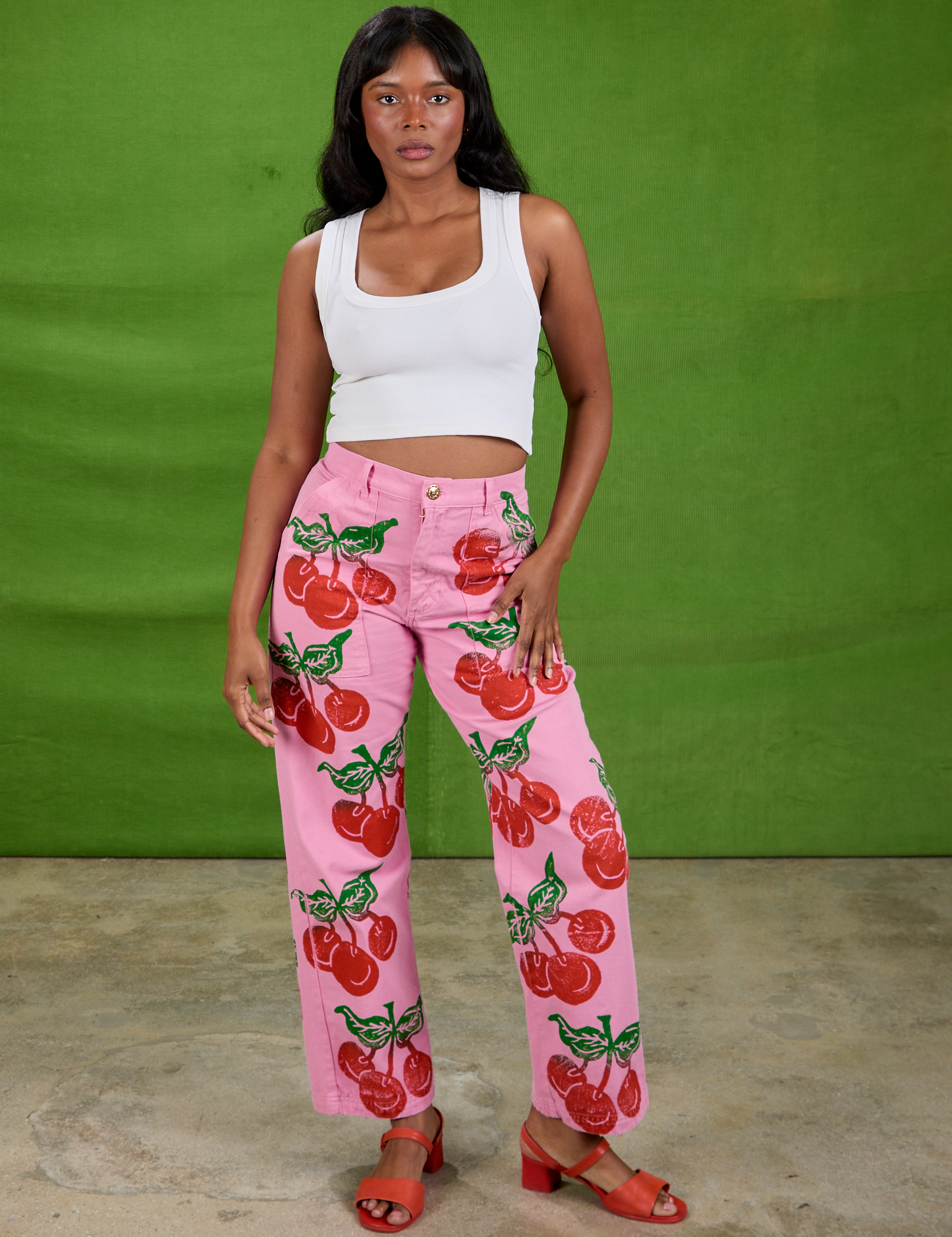 Kandia is 5'3" and wearing XS Cherry Paintstamped Work Pants in Bubblegum Pink paired with a Cropped Tank in Vintage Tee Off-White