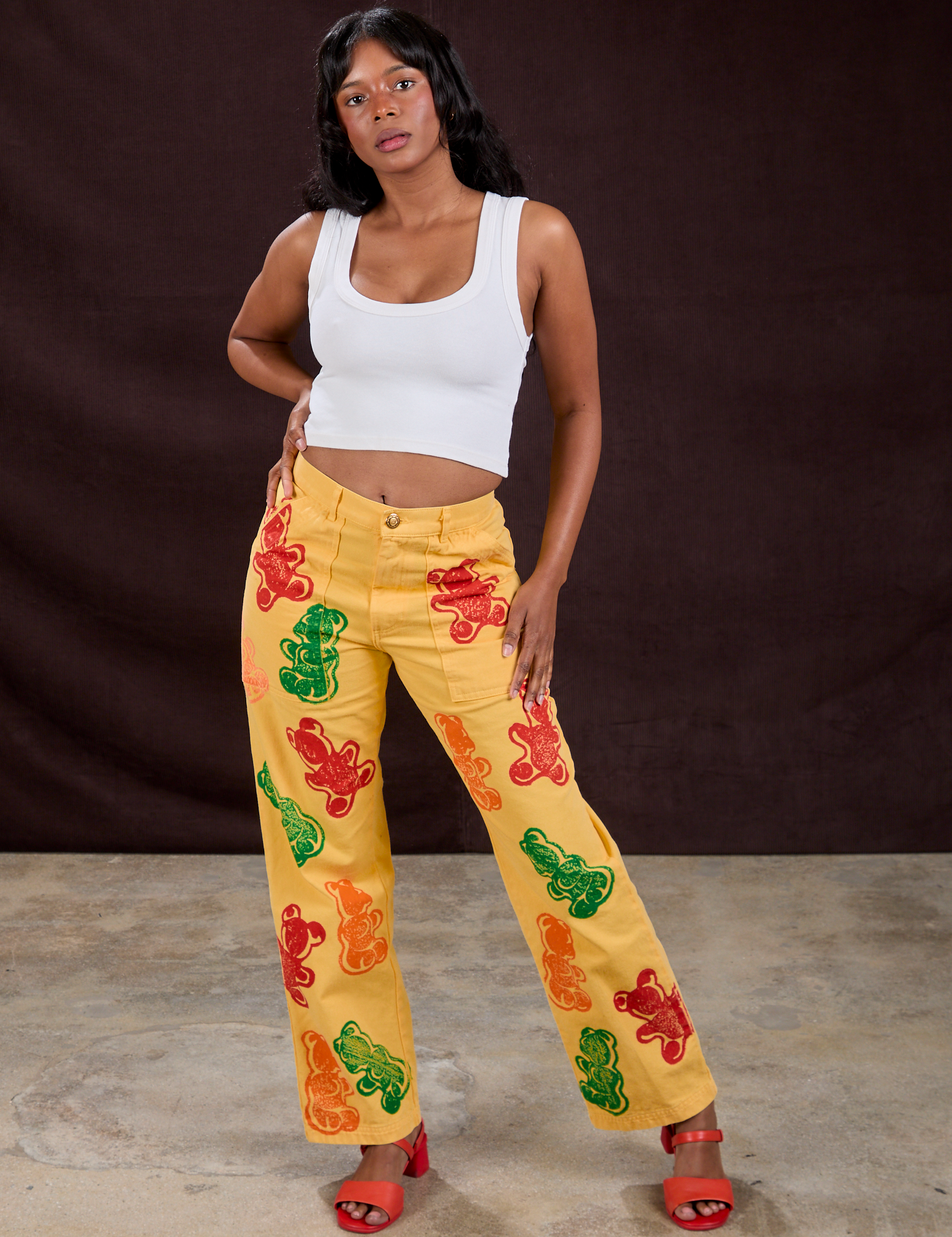 Kandia is 5'3" and wearing XS Gummy Bear Paintstamped Work Pants in Butter Yellow paired with a Cropped Tank in Vintage Tee White