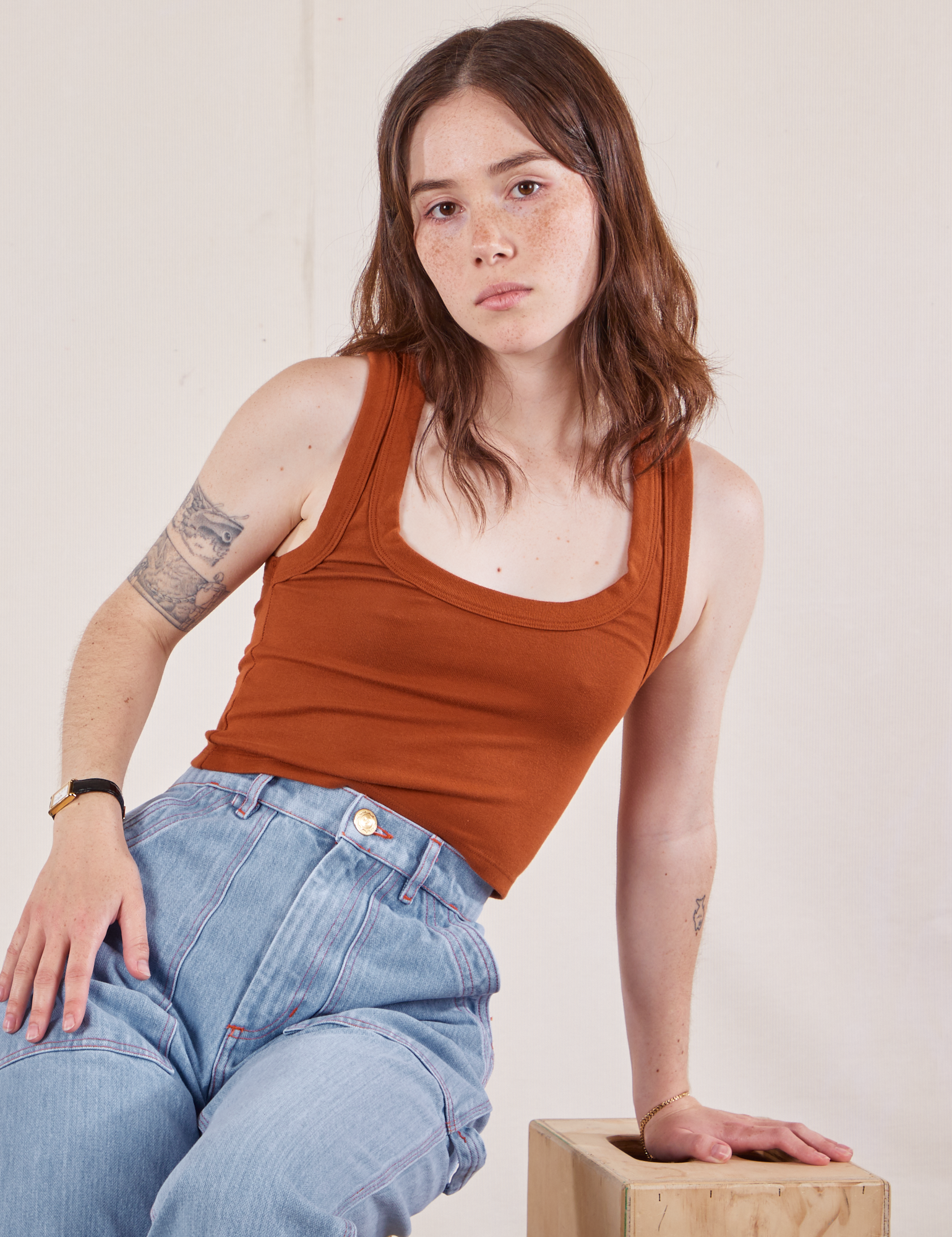 Hana is wearing Cropped Tank Top in Burnt Terracotta and light wash Carpenter Jeans