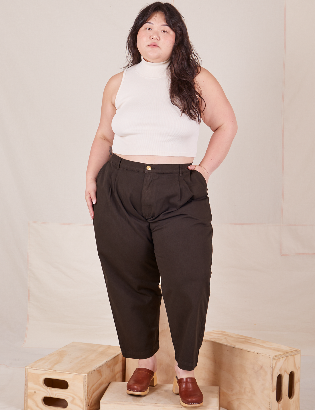 Ashley is 5'7" and wearing 1XL Petite Heavyweight Trousers in Espresso Brown paired with vintage off-white Sleeveless Turtleneck