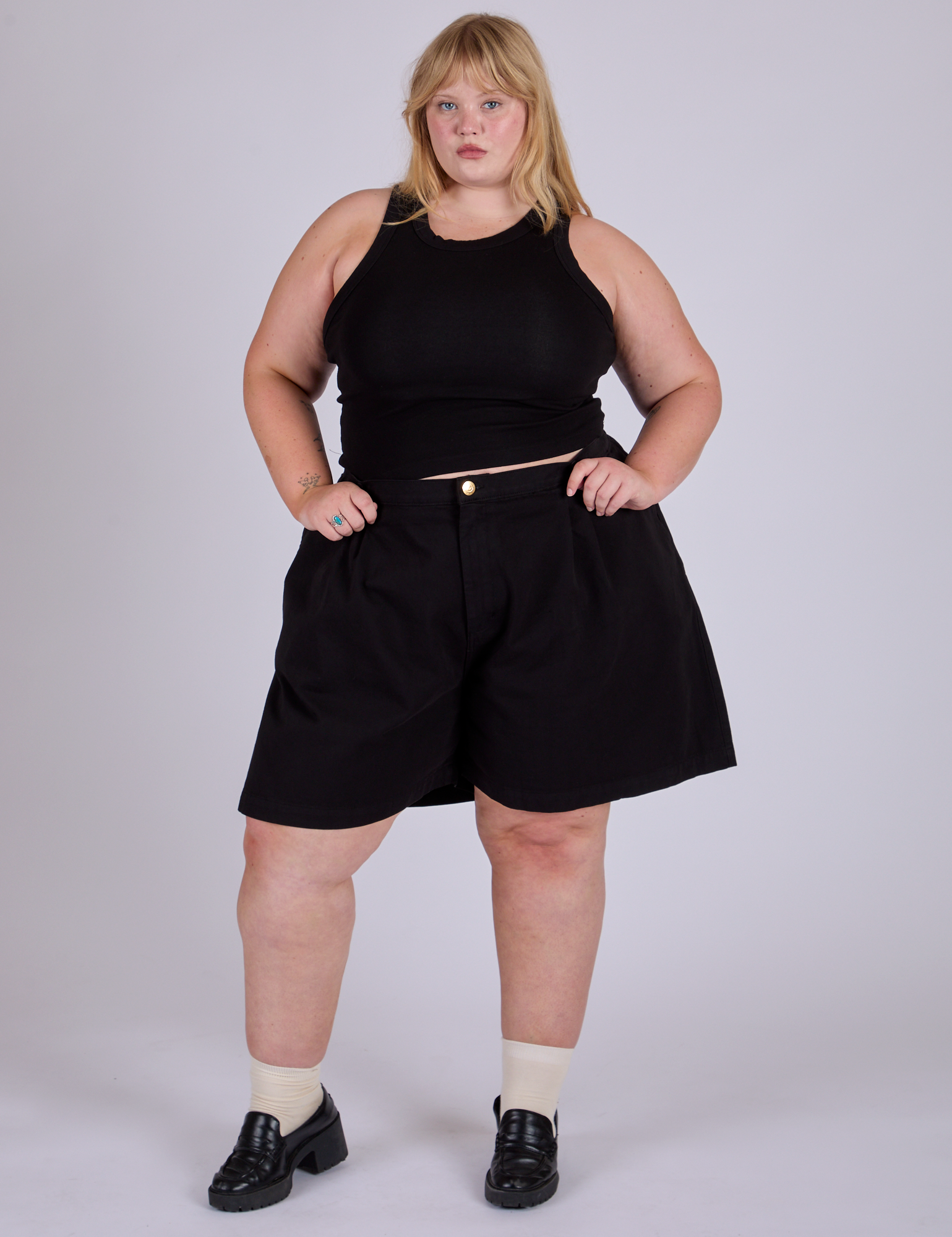 Juliet is 5’7” and wearing 2XL Pleated Trouser Shorts in Basic Black paired with black Racerback Tank