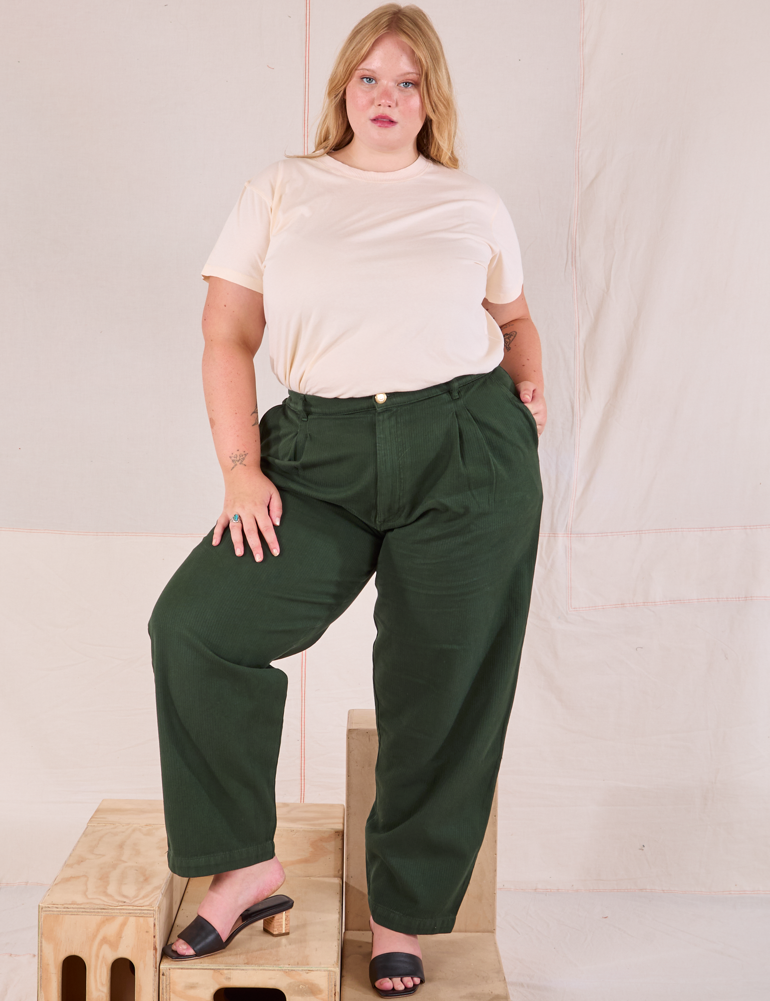 Juliet is 5’7” and wearing 0XL Heritage Trousers in Swamp Green paired with Organic Vintage Tee in vintage tee off-white