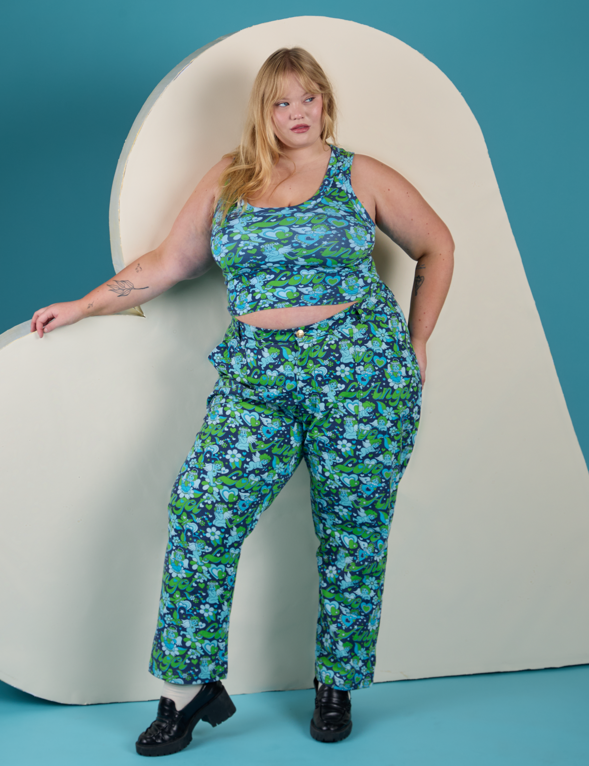 Juliet is 5’7” and wearing 1XL Work Pants in Angel Print paired with matching Cropped Tank