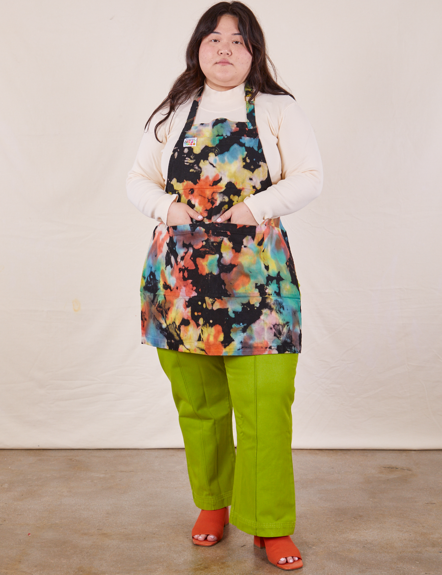 Artist Togs Full Apron in Rainbow Magic Waters worn by Ashley. She has both hands in the apron front pockets.