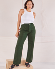 Tiara is 5'4" and wearing S Organic Work Pants in Swamp Green paired with a Racerback Tank in vintage tee off-white