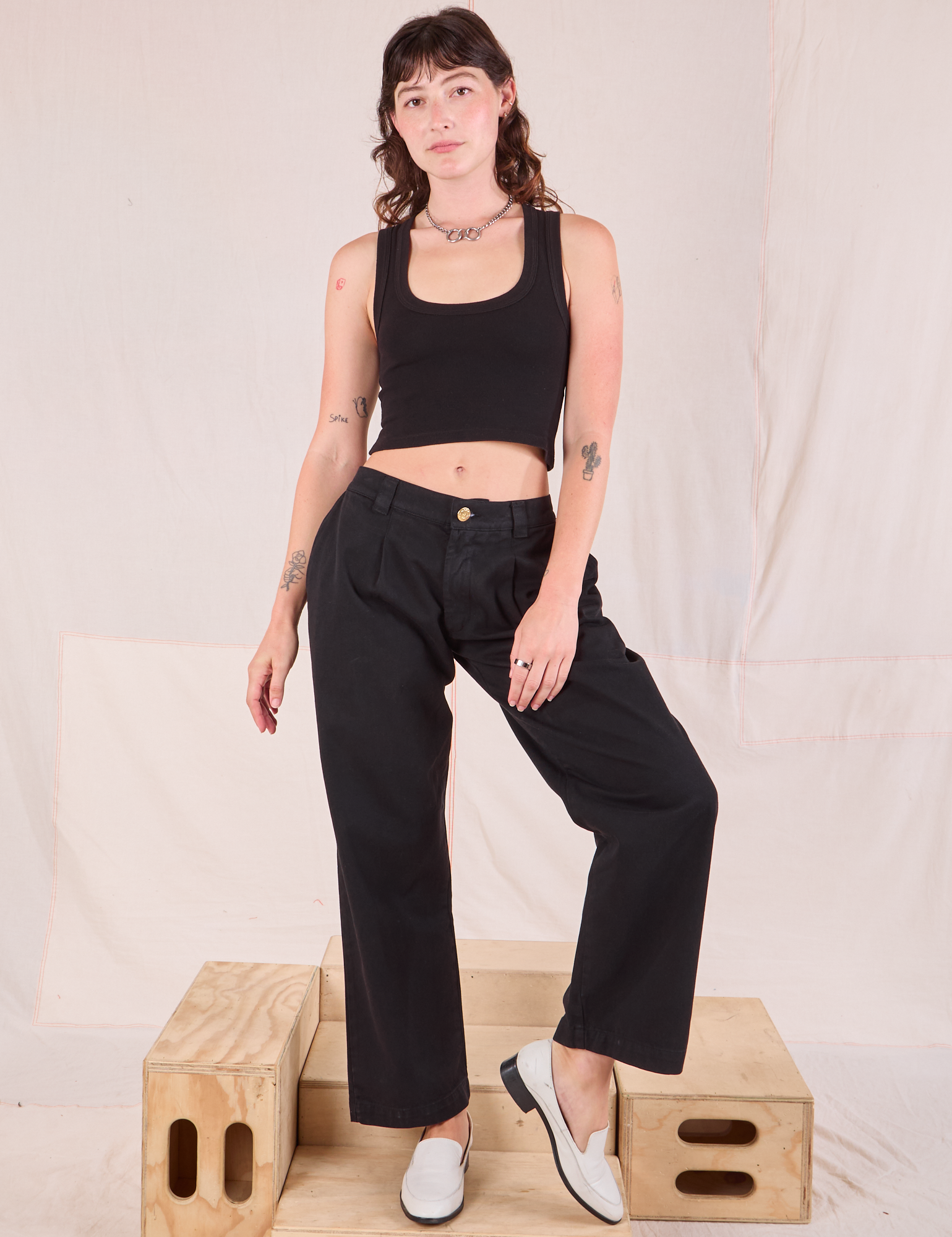 Alex is 5'8" and wearing XXS Mid-Rise Pleated Trousers in Basic Black paired with a black Cropped Tank