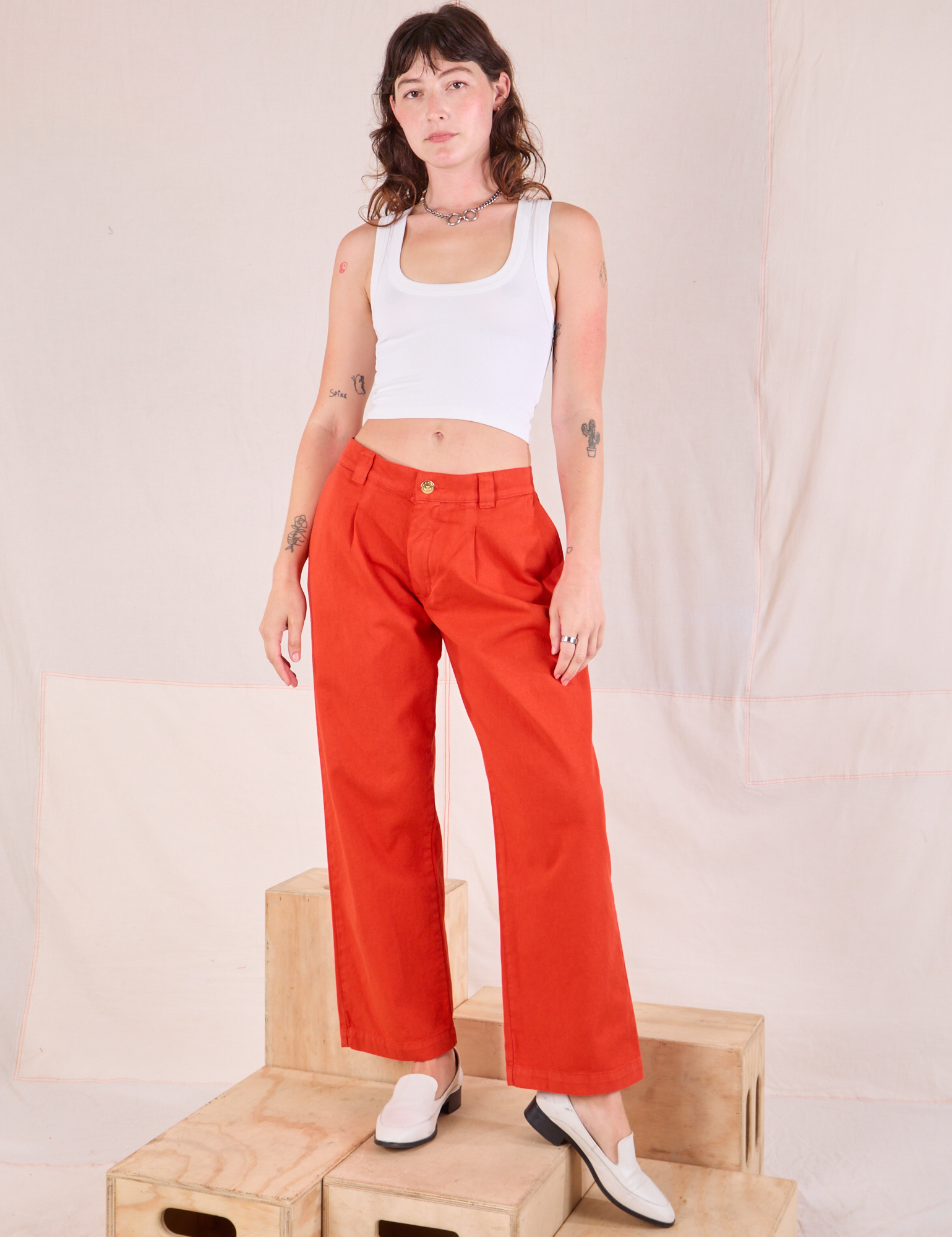 Alex is 5&#39;8&quot; and wearing XXS Mid-Rise Pleated Trousers in Chili Red paired with a Cropped Tank in Vintage Tee Off-White