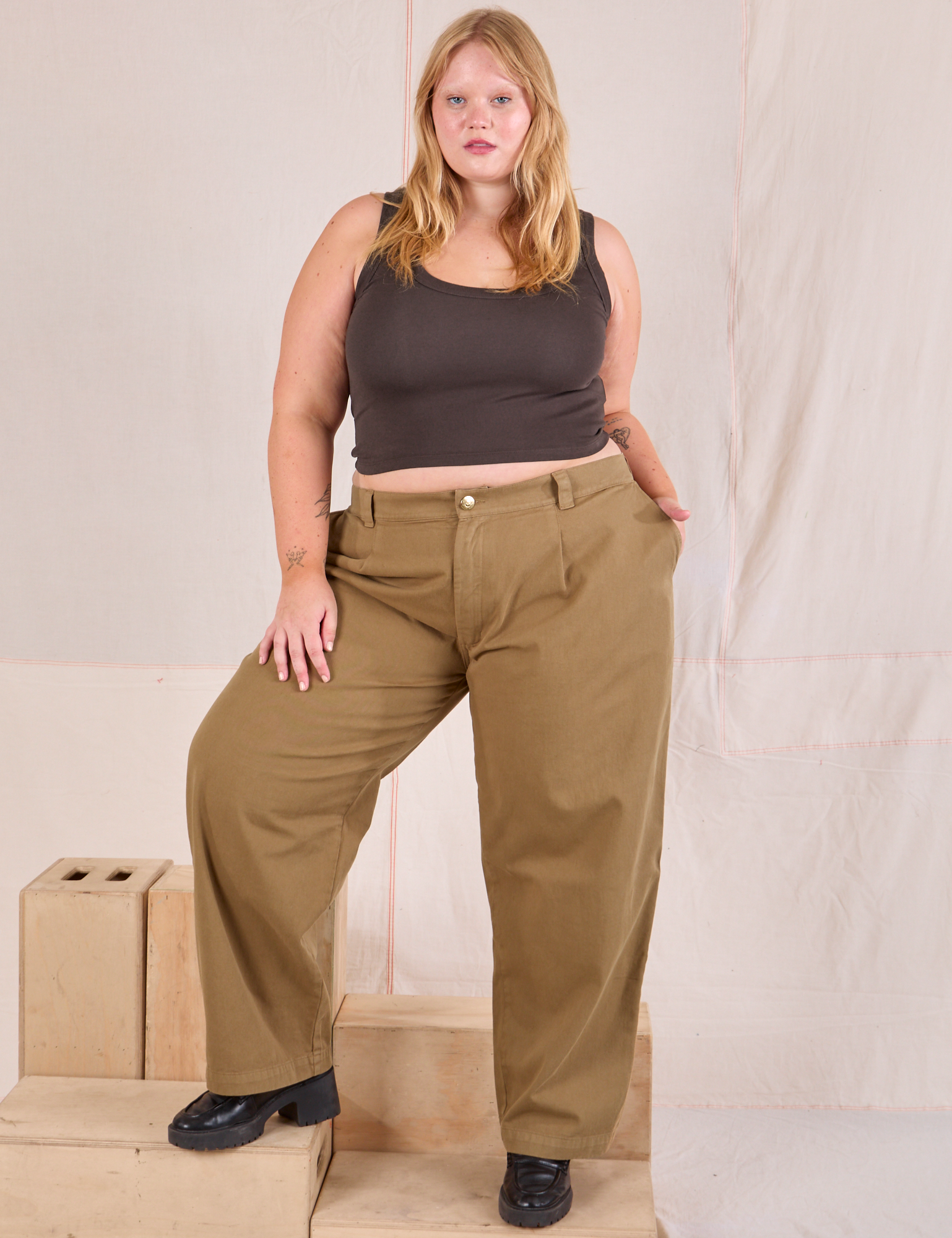 Juliet is 5&#39;7&quot; and wearing 0XL Mid-Rise Pleated Trousers in Desert Brown paired with espresso brown Cropped Tank