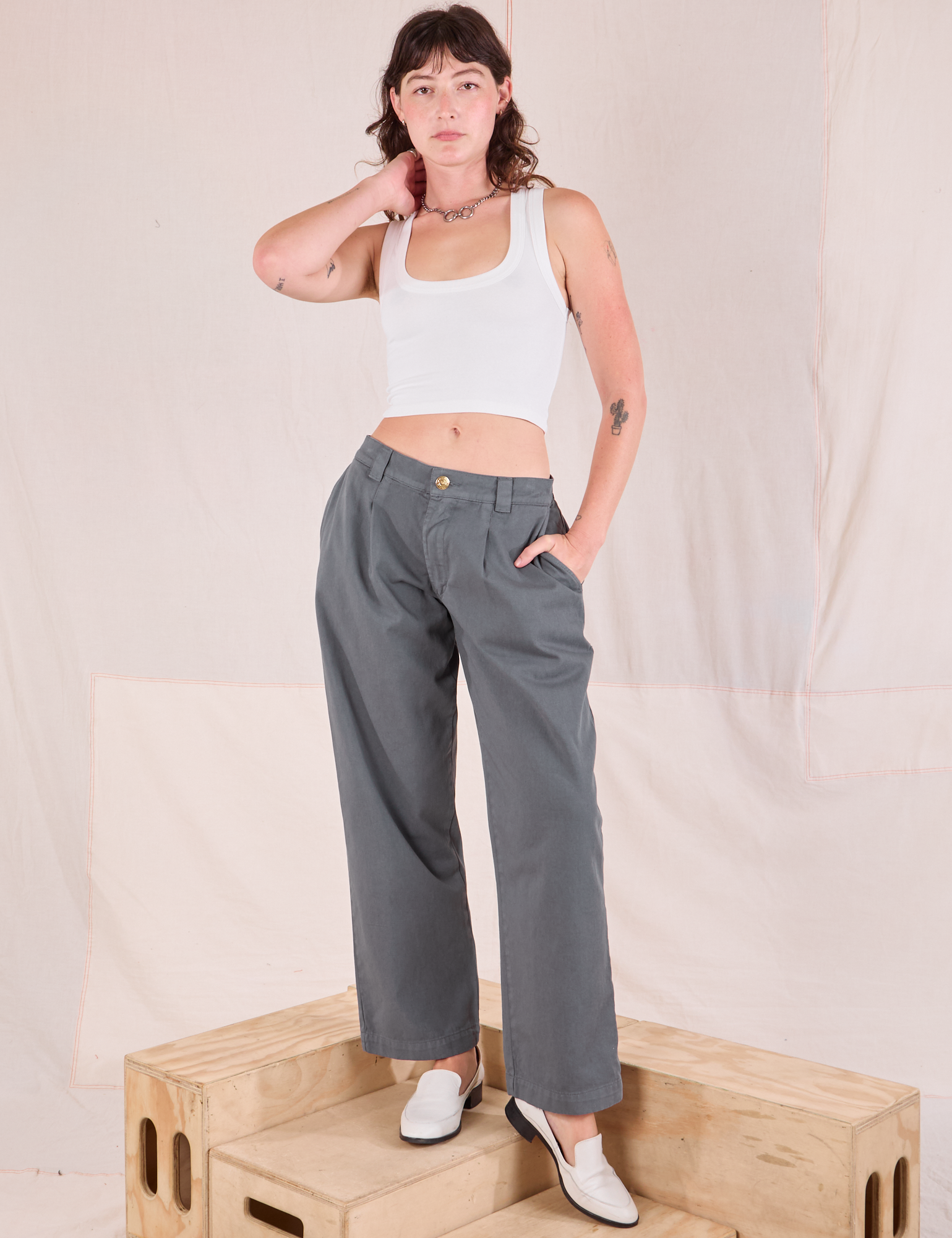 Alex is 5&#39;8&quot; and wearing XXS Mid-Rise Pleated Trousers in Slate Grey paired with Cropped Tank in vintage tee off-white