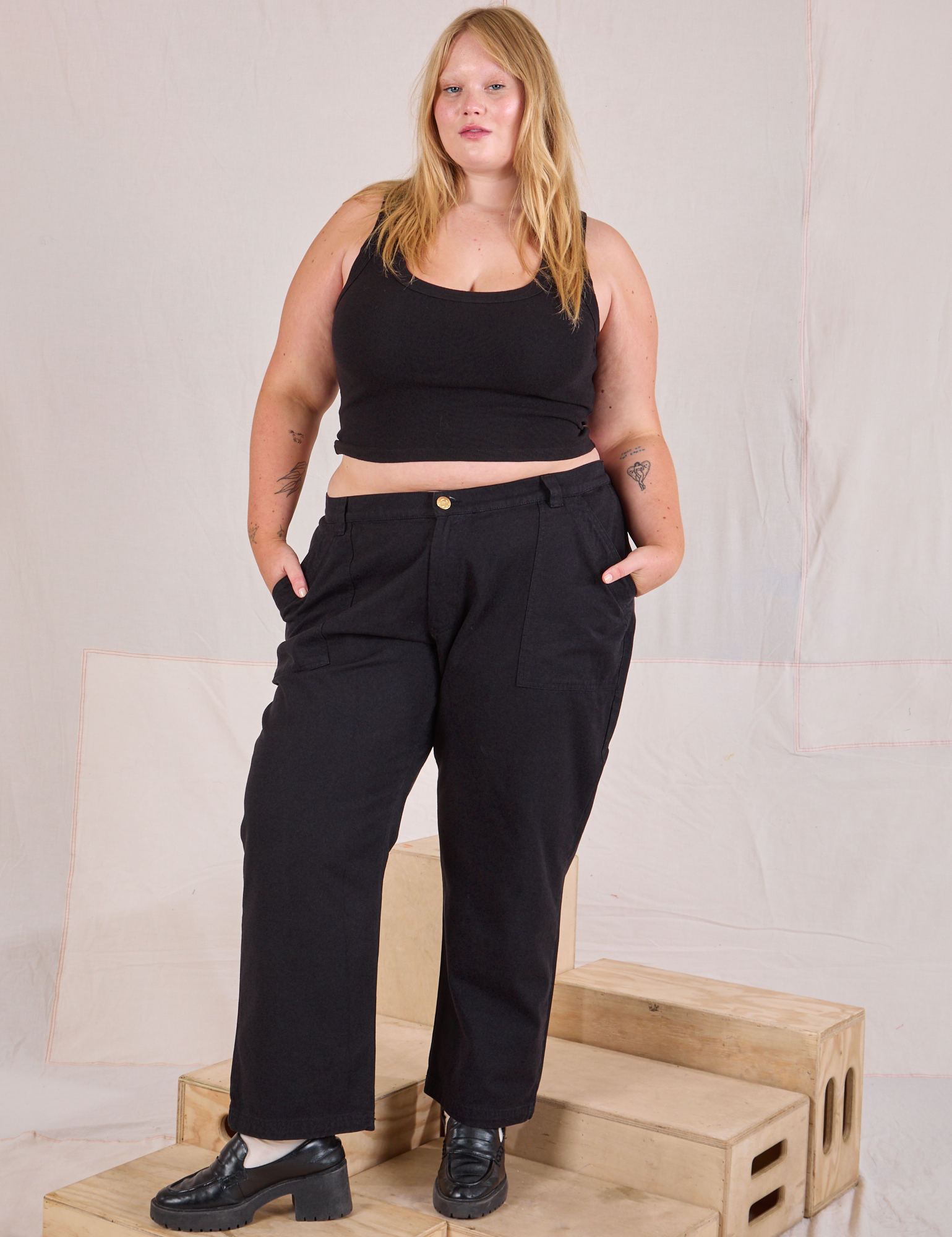 Juliet is 5'7" and wearing 2XL Mid-Rise Work Pants in Basic Black paired with black Cropped Tank