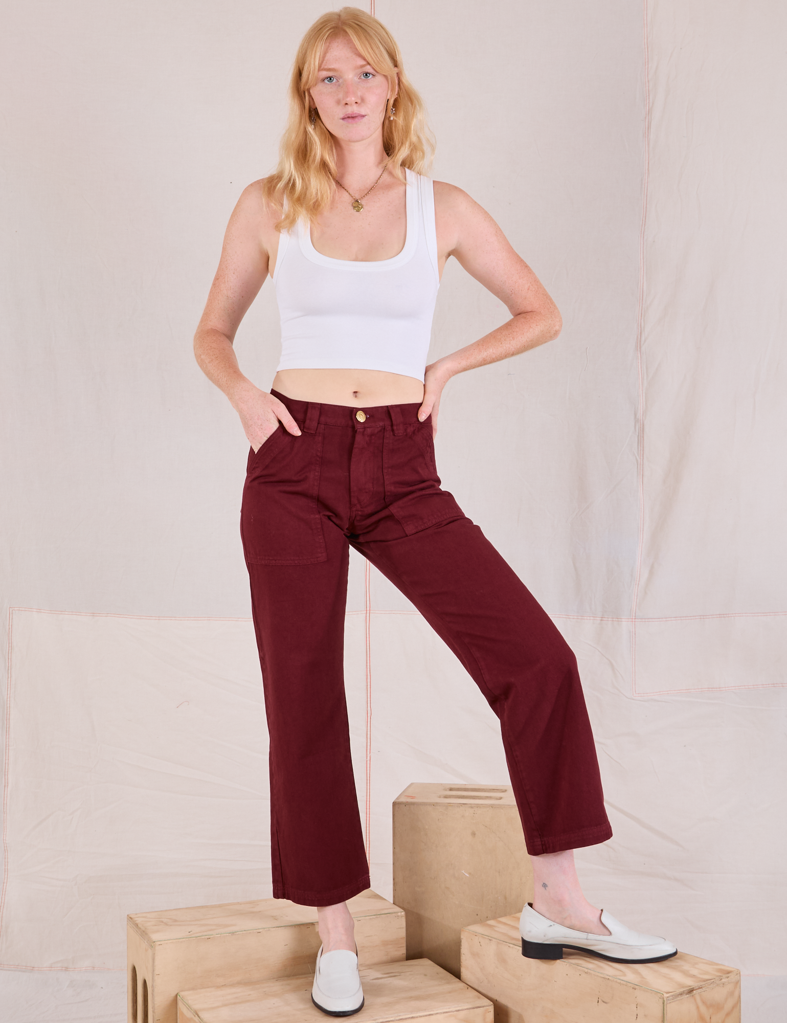 Margaret is 5'11" and wearing XS Mid-Rise Work Pants in Red Wine paired with a Cropped Tank in vintage tee off-white