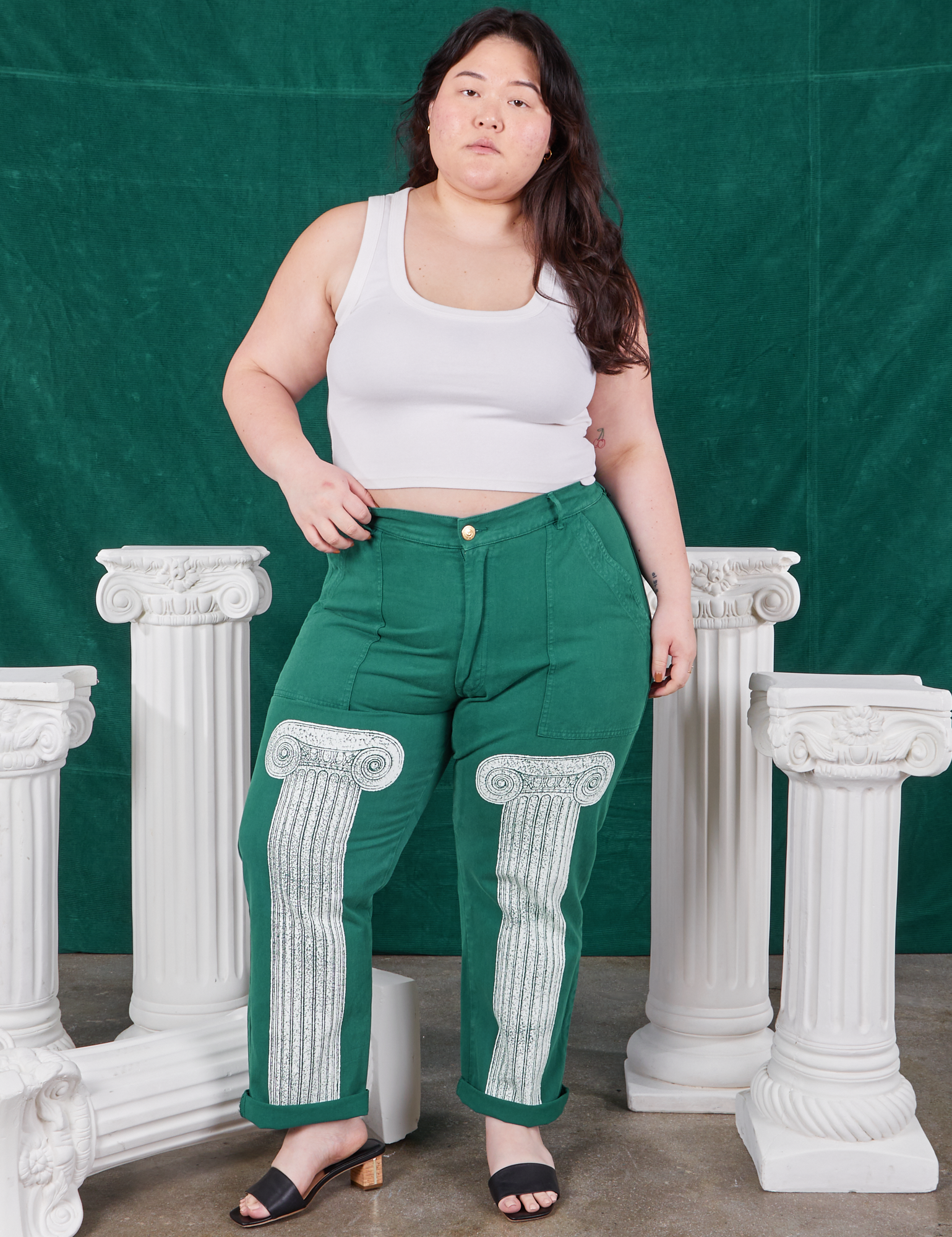 Ashley is 5'7" and wearing 1XL Column Work Pants in Hunter Green paired with vintage off-white Cropped Tank Top
