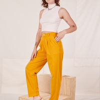 Alex is 5'8" and wearing XXS Organic Trousers in Mustard Yellow paired with vintage off-white Sleeveless Essential Turtleneck