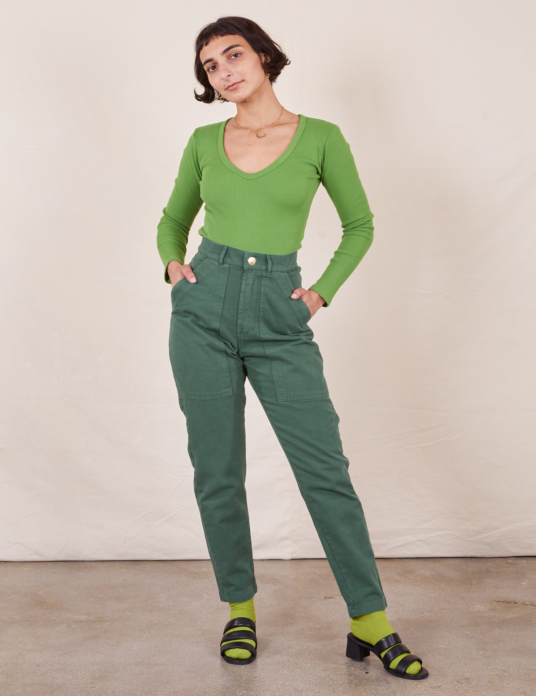 Soraya is 5'2" and wearing XXS Petite Pencil Pants in Dark Emerald Green paired with bright olive Long Sleeve V-Neck Tee